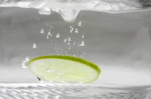 A slice of lime falling into water Stock Photos