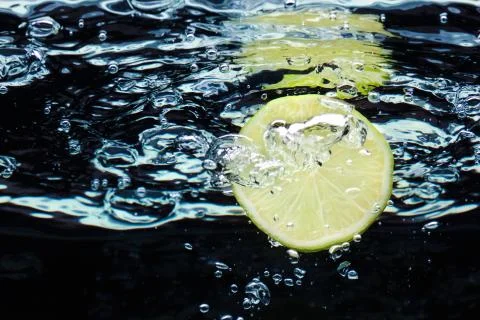 Slice of lime (lemon)  falling in water with air bubbles Stock-Fotos
