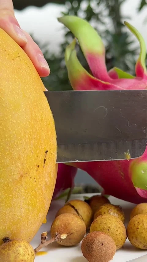 A slice of mango is on a plate with a whole mango on top. The slice of mango is Stock Footage 307339848