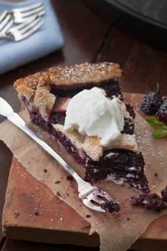 A slice of mulberry pie with cream with a bite taken out Stock Photos