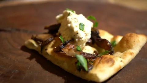 Slice of mushroom flatbread pizza spinning on wooden board, slow motion Stock Footage 124465792