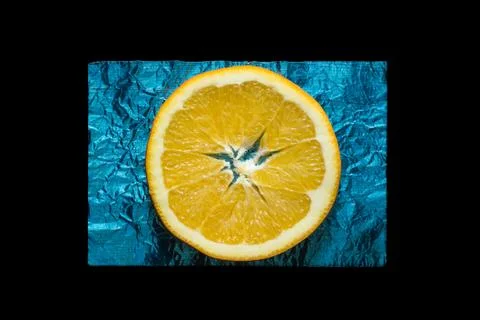 Slice of orange on blue foil Stock Photos