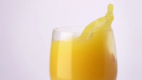 Slice of Orange Falling into a Glass of Orange Juice. Stock Footage 75999970