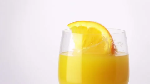 Slice of Orange Falling into a Glass of Orange Juice Stock Footage 120093202