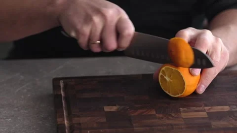 Slice the orange with a knife on a cutting board. Stock Footage 261069642