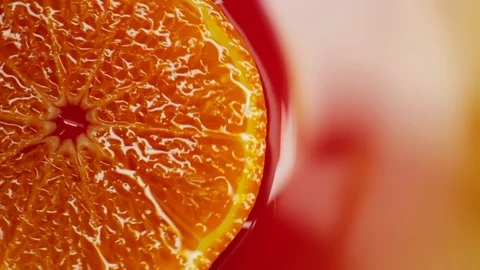Slice of orange rotating close-up on red background Stock Footage 125885180