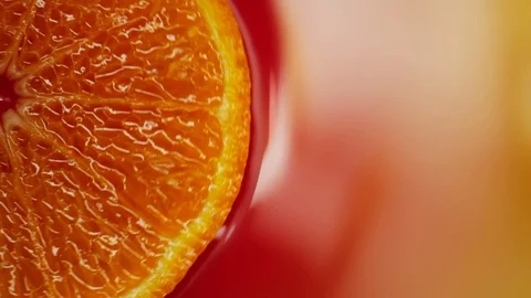 Slice of orange rotating close-up on red background Stock Footage 125885191