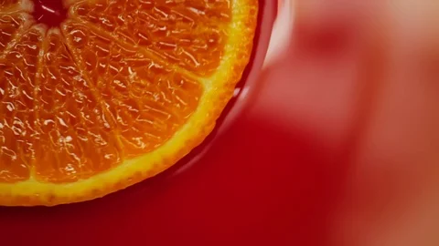 Slice of orange rotating close-up on red background Stock Footage 125885281