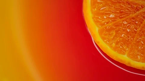 Slice of orange rotating close-up on red background Stock Footage 125885348