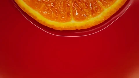 Slice of orange rotating close-up on red background Stock Footage 125885390