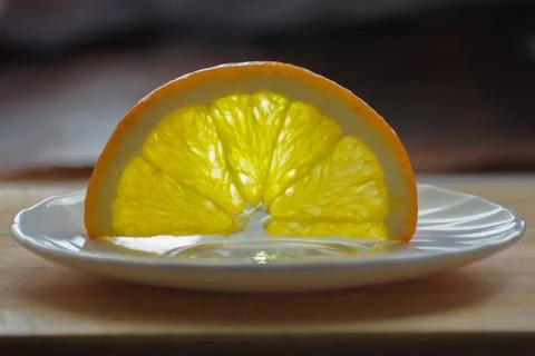 A slice of an orange upside down on the white plate Stock Photos
