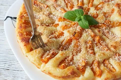 A slice of peach pie with a fork and mint on a white plate. Stock Photos