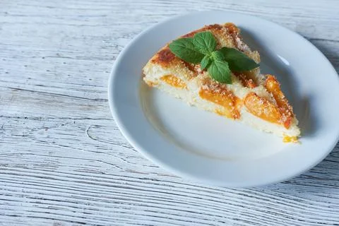 Slice of peach pie on a white plate on a wooden background Stock Photos
