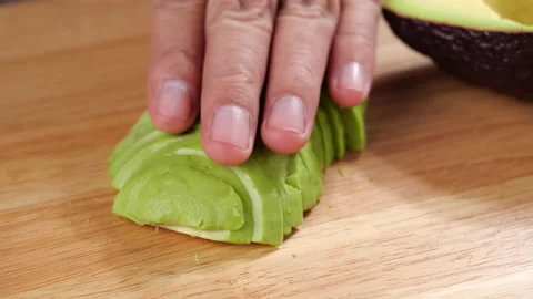 Slice peeled avocado on cutting board. Preparing healthy food Stock-Footage 140251772