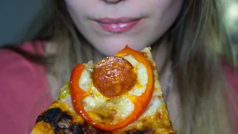 A slice of pepperoni pizza, in the background a blurred face of a girl Stock Photos
