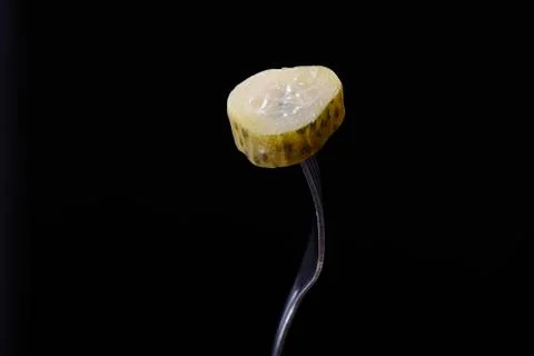 Slice of pickled cucumber on fork isolated on a black background Stock Photos