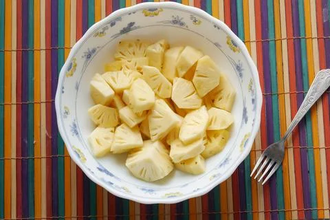 Slice of pineapple in bowl on blue background Stock Photos