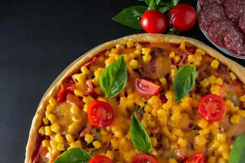 Slice of pizza with cherry and basil on a black background. Ingredients for p Foto stock