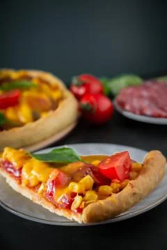 Slice of pizza with cherry and basil on a black background. Ingredients for p Stock Photos