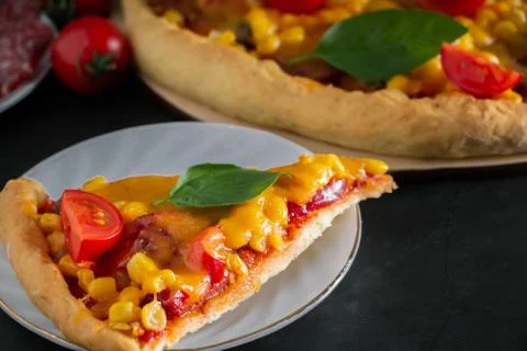 Slice of pizza with cherry and basil on a black background. Ingredients for p Stock Photos