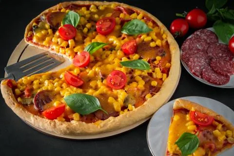 Slice of pizza with cherry and basil on a black background. Ingredients for p Stock Photos