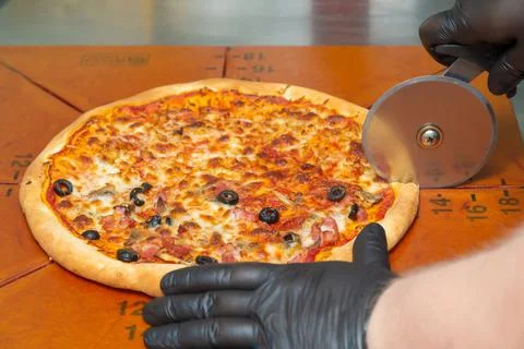 Slice the pizza with the wheel. Stock Photos