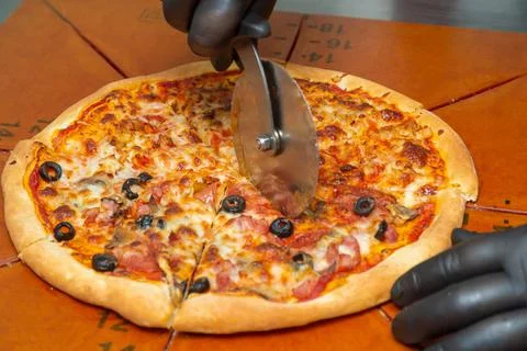 Slice the pizza with the wheel. Stock Photos