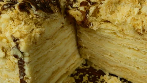Slice of puff appetizing Napoleon cake cut into two parts with metal knife. Stock Footage 131849517
