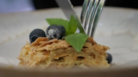 Slice of puff appetizing Napoleon cake cut into two parts with metal knife Video stock 135340252