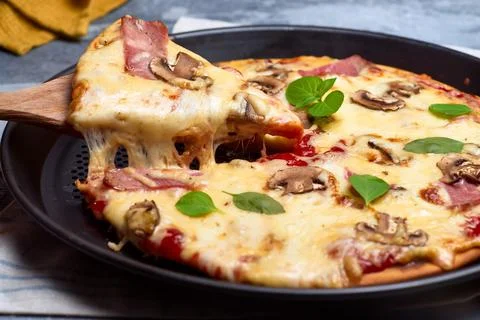 Slice pulloff from homemade pizza with ham and mushroom Stock Photos