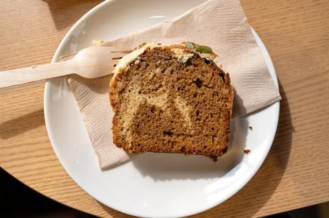 Slice of pumpkin cake with wooden fork on white plate Stock Photos