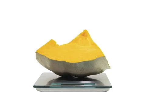 A slice of pumpkin on a digital scale on a white background Stock Photos