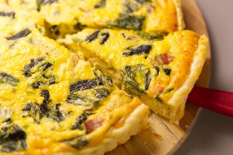 A slice of quiche with bacon and spinach Foto stock
