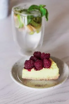 Slice of raspberry cake and non-alcoholic mojito in the cafe. Summer food Stock Photos