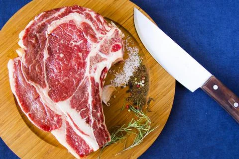 Slice of raw beef meat with spices and a knife on a table Stock Photos