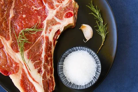 Slice of raw beef steak on a kitchen table with spices and herbs Stock Photos