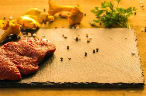 Slice of raw beef steak with spice on dark background Stock Photos