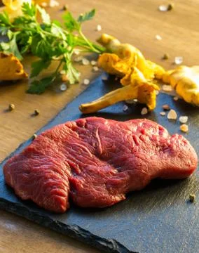 Slice of raw beef steak with spice on dark background Stock Photos