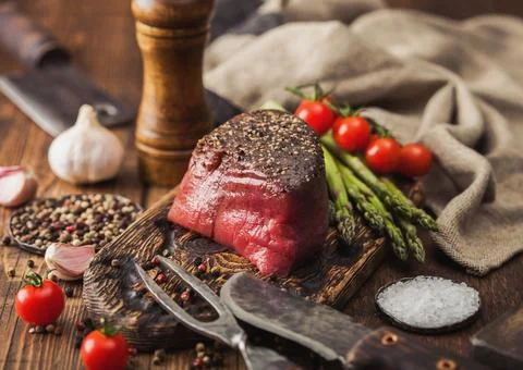Slice of Raw Beef Topside Joint with Salt and Pepper on wooden chopping board Stock Photos