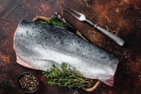 Slice of Raw cut salmon fish in a wooden tray with thyme. Dark background. Top Stock Photos