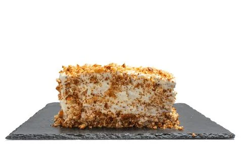 A slice of rectangular cake with whipped cream and crumb decoration. Stockfoto's