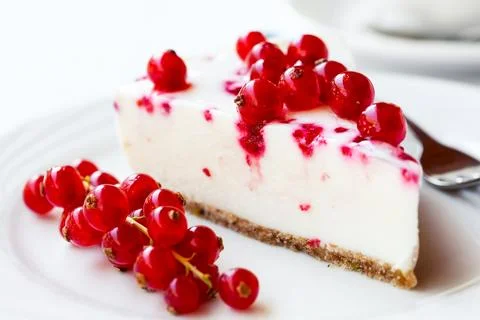 A slice of red currant cheesecake, served on a white plate. Stock Photos