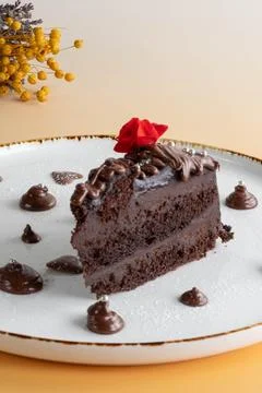 A slice of rich chocolate layer cake topped with a red flower Stock Photos