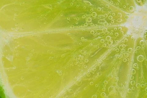Slice of ripe lime in water. Close-up of lime in liquid with bubbles. Slice.. 스톡 사진