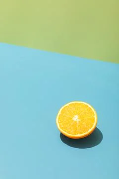 Slice of ripe yellow lemon on a bright blue and green background, hard light Stock Photos