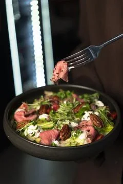 Slice of Roast Beef on Fork Above Fresh Salad 写真素材
