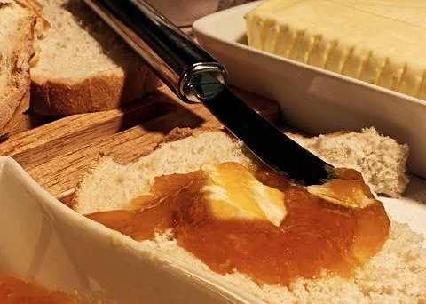 Slice of rustic bread with apricot jam and melting butter Stock Photos