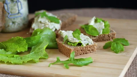 Slice of rye bread with cheese spread and greens on the table Stock Footage 310937647