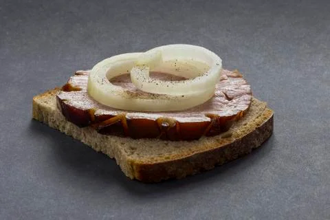 Slice of rye bread with ham and onions on a gray background. Dusted with blac Stock Photos