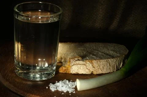 Slice of rye bread with young green onion and glass of vodka Stock Photos